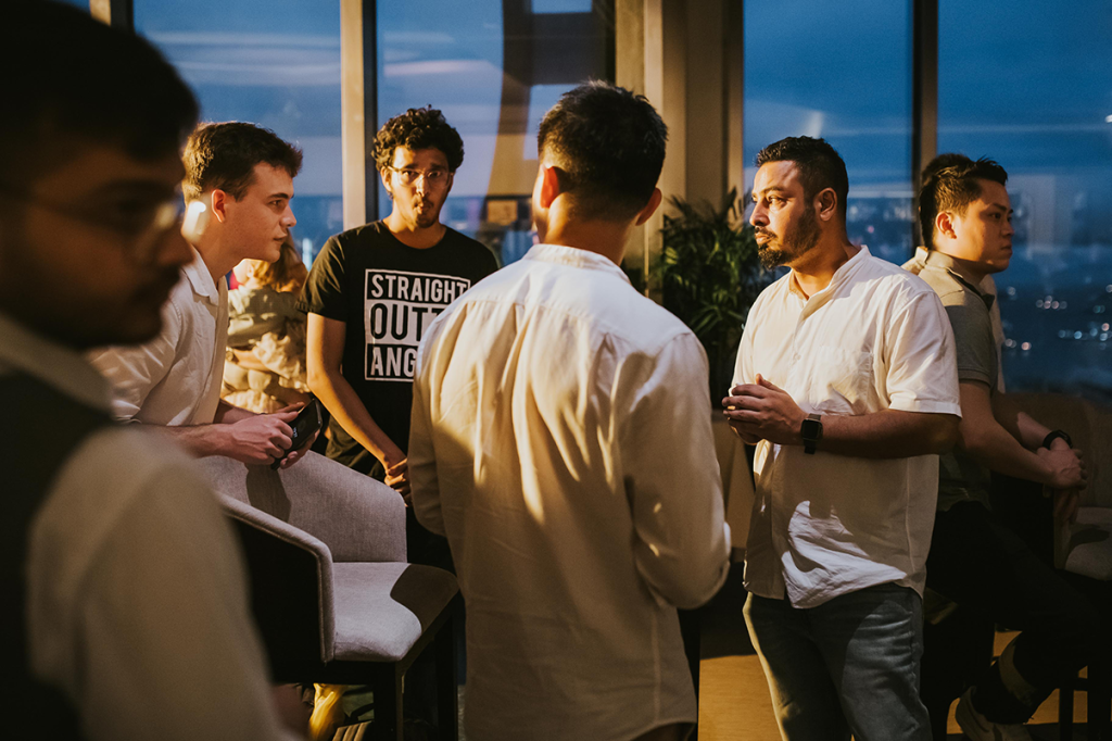 Guests networking by the windows at an evening event at 1-Arden