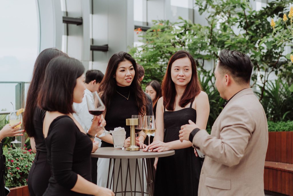 Guests chatting over wine at a rooftop networking event at 1-Arden
