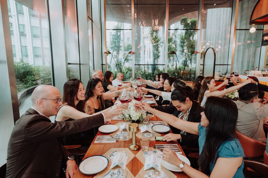 Team raising a toast at a long-table corporate dinner at 1-Arden