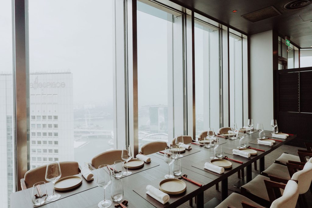 Private dining long table set beside floor-to-ceiling windows with city views at 1-Arden