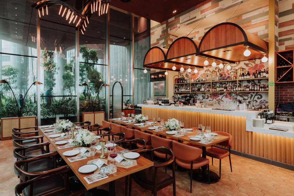 Long tables set for a corporate group dinner in a 1-Arden restaurant at CapitaSpring