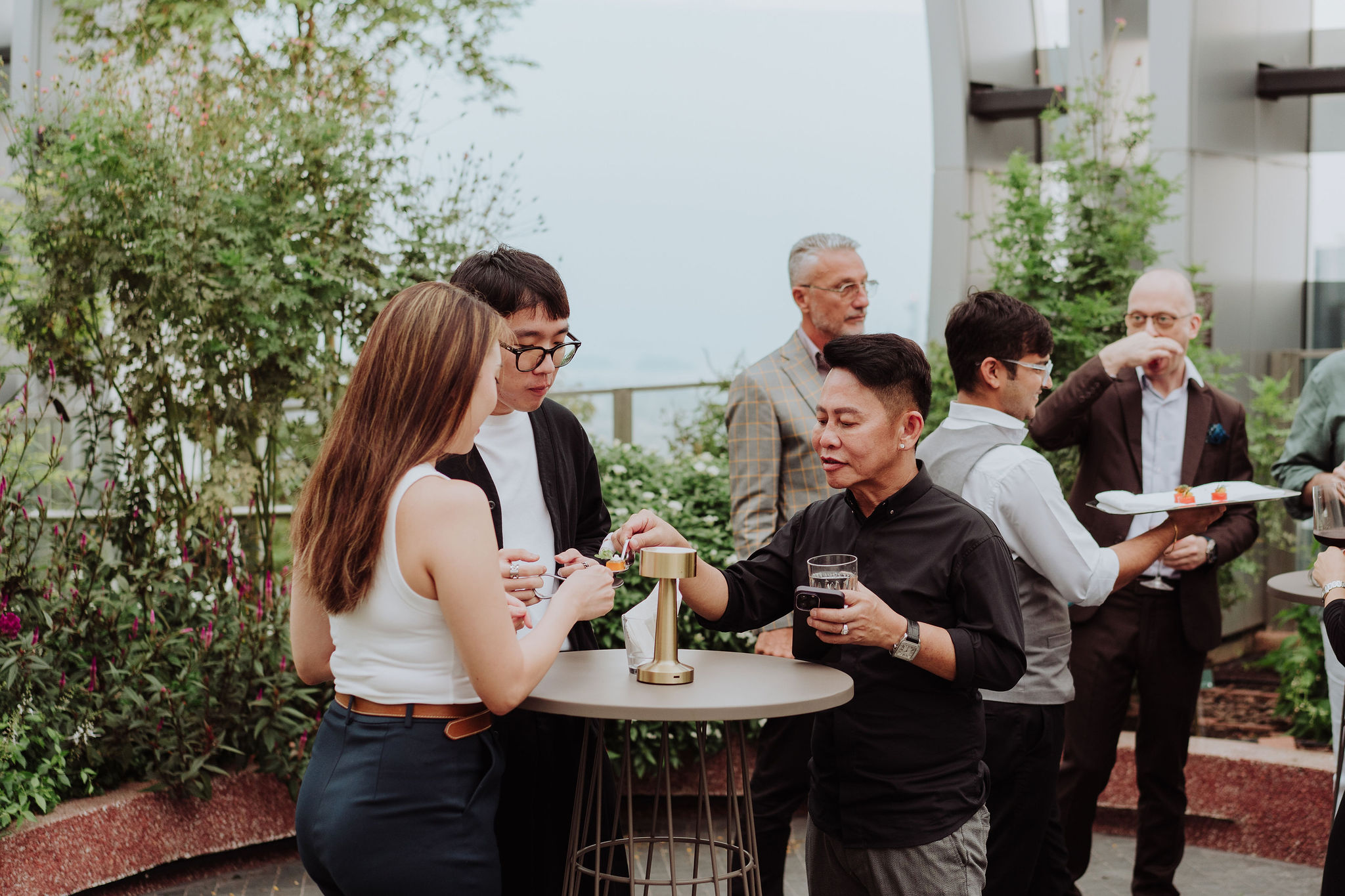 Guests networking at a rooftop corporate event in the 1-Arden sky garden at CapitaSpring, Singapore
