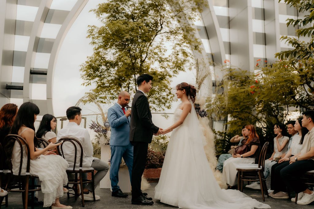 Couple exchanging vows at a sky garden solemnisation with guests seated on the 1-Arden rooftop, Singapore