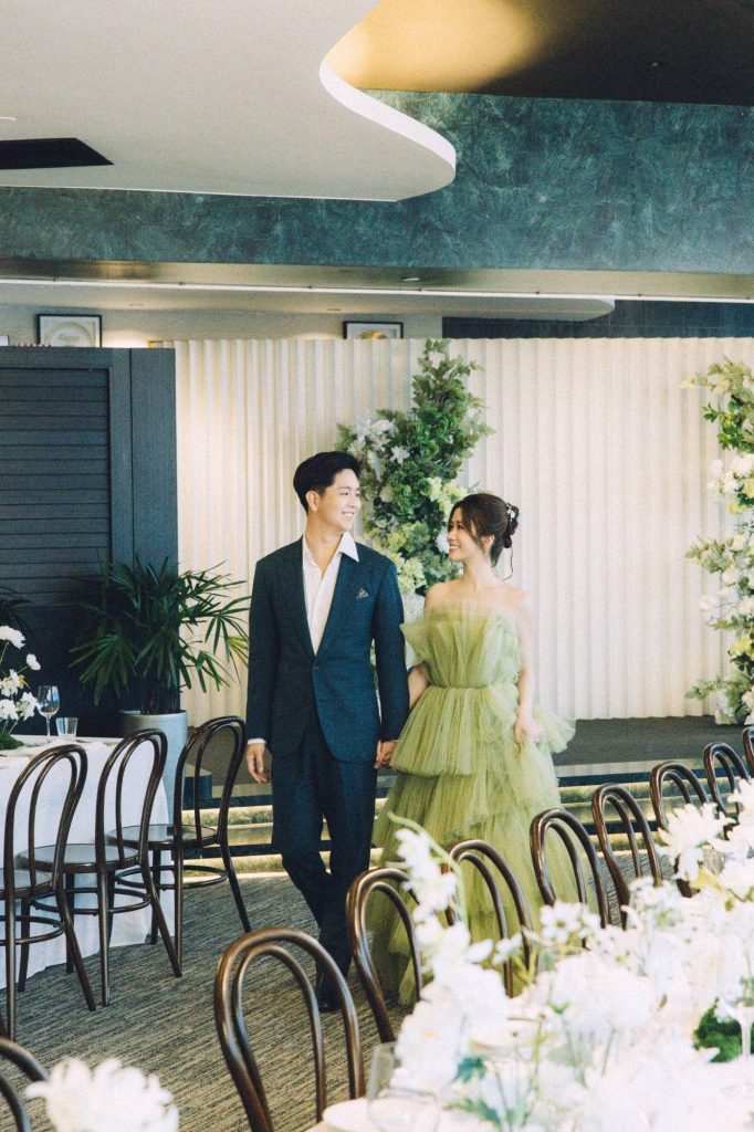 Couple walking through the 1-Arden banquet hall set for a wedding reception at CapitaSpring